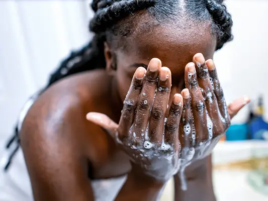 A woman with soapy hands in front of her face