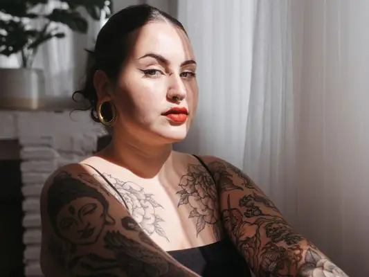 woman sitting next to window with tattoos on arms