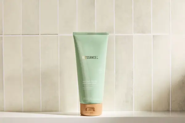Biossance Squalane + Enzyme Sugar Body Scrub on a bathroom ledge