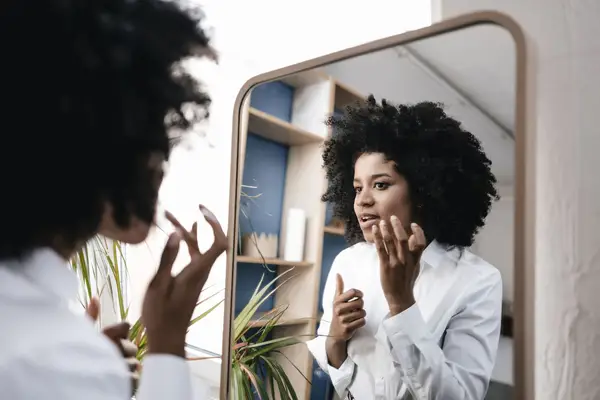 woman looking at sebaceous filaments in mirror