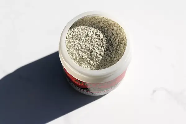 Open container of Aztec Secret Indian Healing Clay displayed on marble countertop