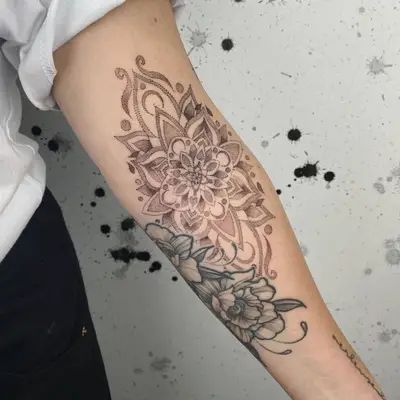 Person with a large mandala tattoo with flowers on the arm