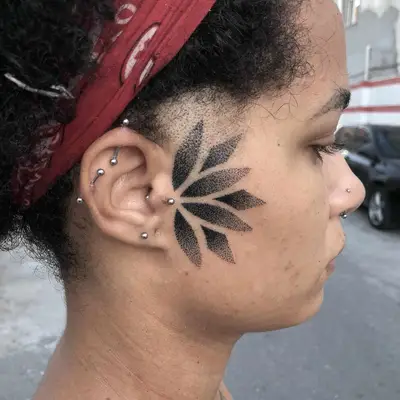 Person with a gradient dotted mandala tattoo on the side of the face
