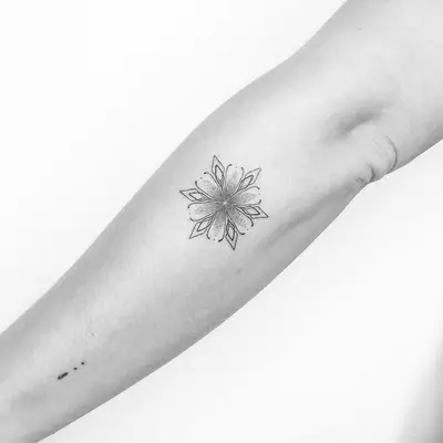 Person with a delicate mandala tattoo on the arm near the elbow