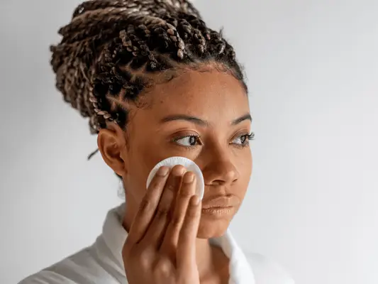 A woman using a cotton round on her face