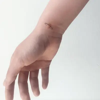 Person with a small planet tattoo on the inner wrist