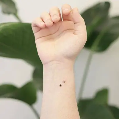 Person with a simple pair of stars wrist tattoo