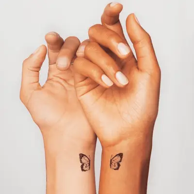 Wrists with half a butterfly tattoo on each