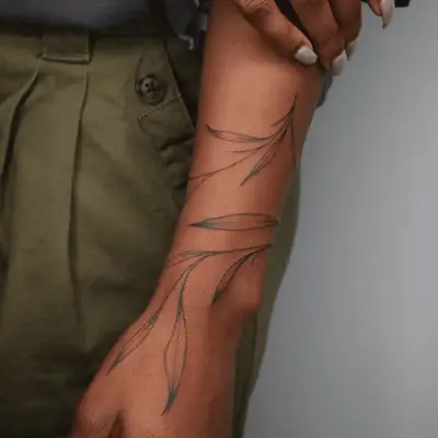 Person with a winding olive branch tattoo