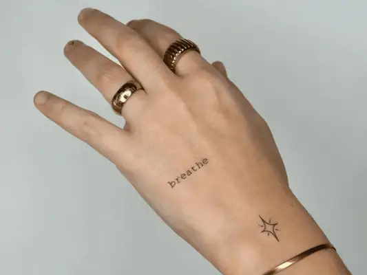 A hand wearing gold wrings and a bracelet with a 
