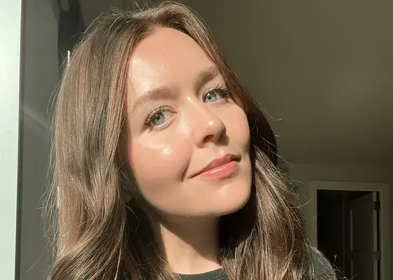 woman in 20s with glowy skin smiling at camera