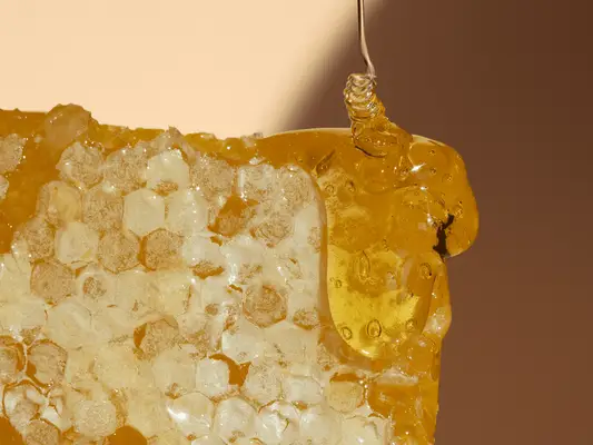close up of honey dripping onto honey comb