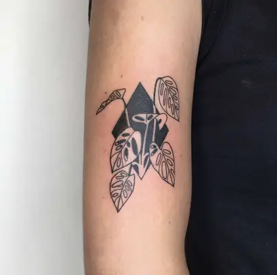 Black diamond and negative space leafy plant outline tattoo
