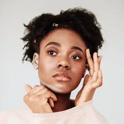 woman with short curly hair touching face