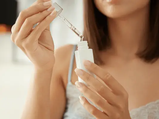 Close up of a woman holding a skincare dropper bottle