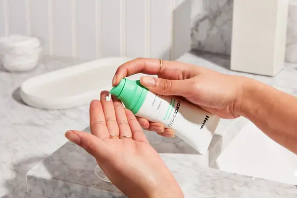 Hand dispensing Hero Cosmetics Superlight Sunscreen SPF 30 onto other hand