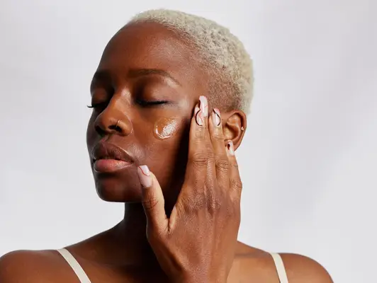 woman applying moisturizer to face