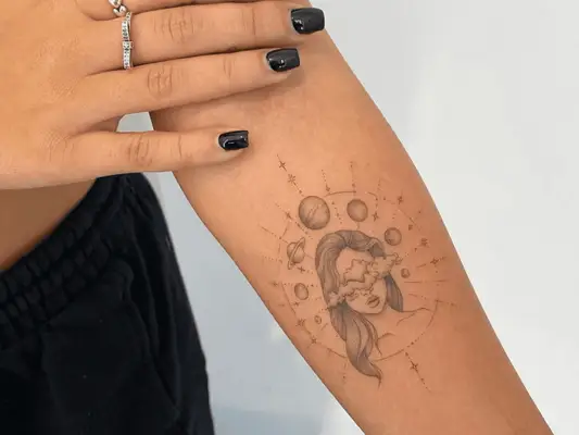 A forearm with a compass tattoo design featuring the planets and a woman