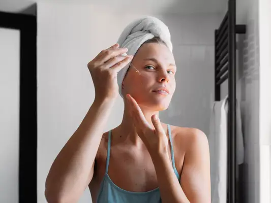 Close up of a woman applying facial serum