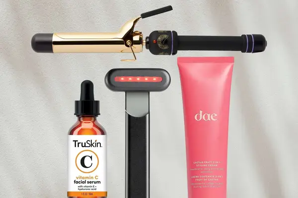 Curling iron, skincare tool, vitamin c serum, and styling cream on gray background