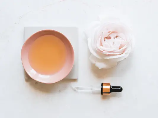 Composed shot of a rose, a bowl with oil and a dropper