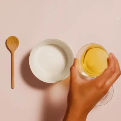 Ingredients for DIY sugar scrub laid out on pink surface