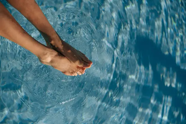 woman soaking feet in pool