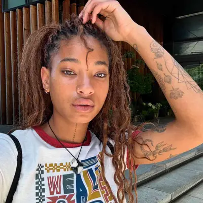 Willow Smith holding up arm to showcase sticker sleeve tattoos