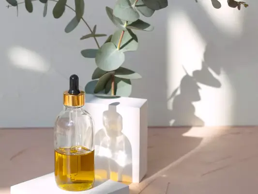 hair oil in bottle with dropper and eucalyptus plants