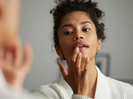 Woman applying lip balm in mirror