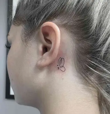 Close-up of semicolon butterfly tattoo behind woman