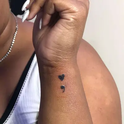 Close-up of heart-shaped semicolon tattoo on wrist