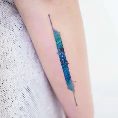 Arm with blue and green watercolor tattoo featuring semicolon design