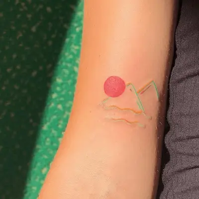 colorful mountain tattoo in reds and blues