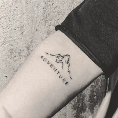 mountain tattoo with the word adventure beneath