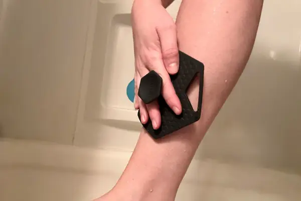 A person using the Tooletries The Body Scrubber on their legs in the shower