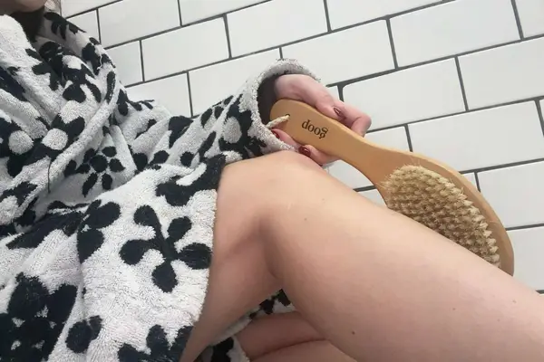 a tester holding goop G.Tox Ultimate Dry Brush while wearing a robe