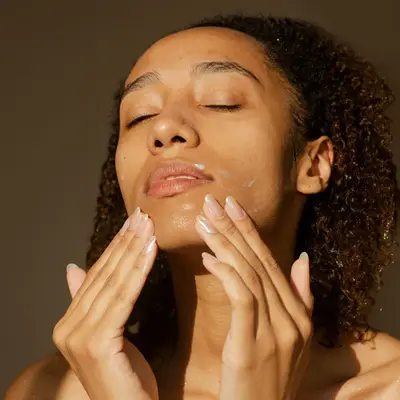 person applying moisturizer to face