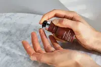 A person squeezes Dr. Dennis Gross Advanced Retinol + Ferulic Triple Correction Eye Serum onto their finger