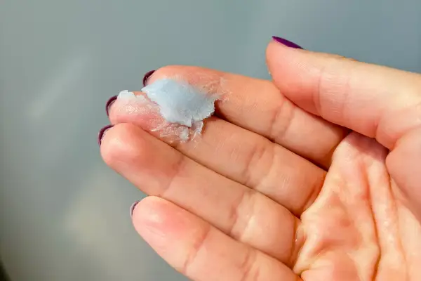 A hand holding gray cleansing balm