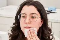 Person dabbing their chin with an oil blotting sheet 