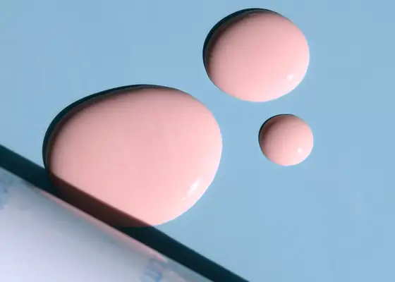 close up of pink sulfur skincare drops on blue background