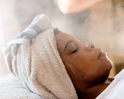 woman relaxing & enjoying a facial treatment at a beauty salon.
