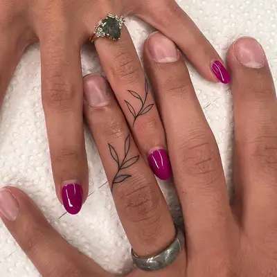 Close-up of two hands with fine line plant matching tattoos on fingers
