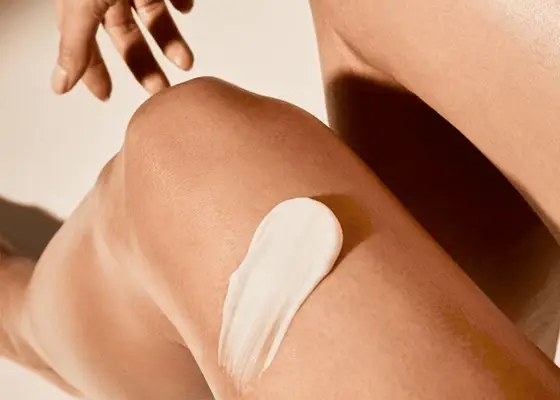 A bare leg bent with a swipe of white cream on the thigh