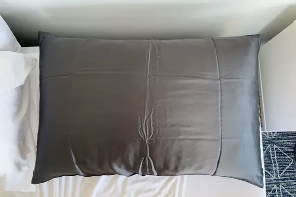 Collage of a pink Slip pure silk pillowcase and a white silk pillowcase displayed with taupe bed linen and pillows