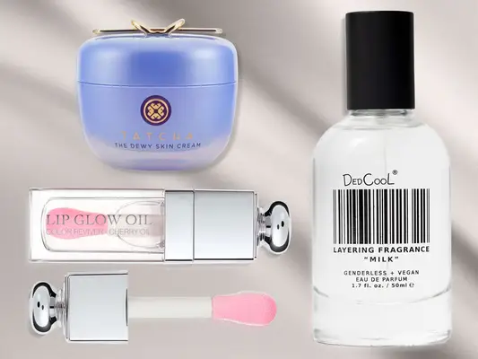 Dior Lip Oil, Tatcha Moisturizer, and DedCool Fragrance on a grey silky background