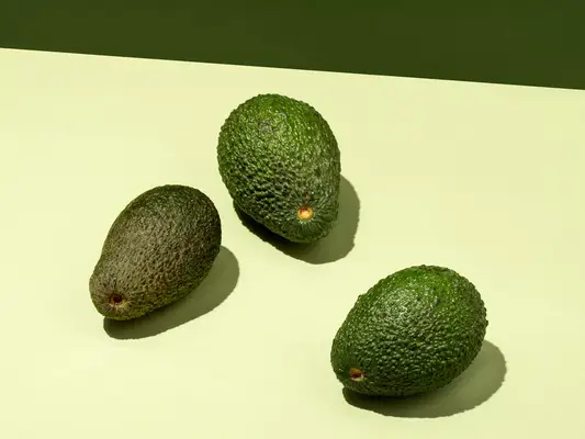 three avocados on a light green background