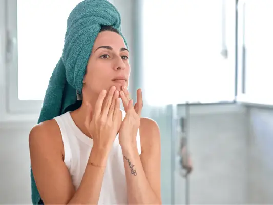 Woman touching her chin and looking in mirror
