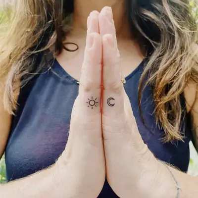 Small sun and moon tattoos on outer pinky fingers
